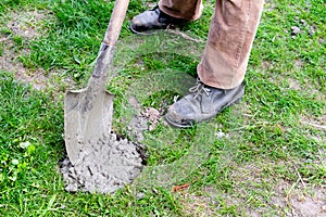 Worker builder man pour in cement solution with rubble, slurry, concrete mortar in pit or hole with shovel. Preparing