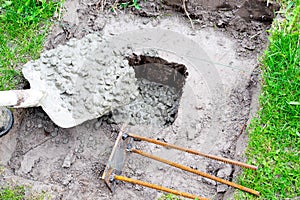 Worker builder man pour in cement solution with rubble, slurry, concrete mortar in pit or hole with shovel. Preparing