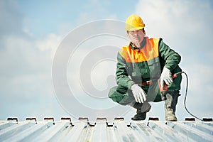 Worker builder roofer at metal profile work