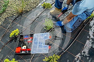 Worker Building Drip Irrigation System in a Backyard Garden