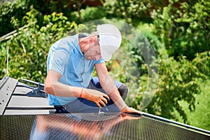 Worker building photovoltaic solar panel system on rooftop of house with help of hex key.