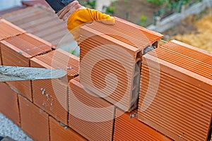 Worker builds a brick wall for house construction. Worker building a brick wall using mortar.