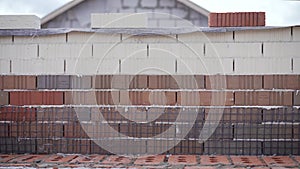 Worker builds a wall of colored brick. Worker in Close up of industrial bricklayer installing bricks and mortar cement brick on