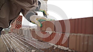 Worker builds a wall of colored brick. Worker in Close up of industrial bricklayer installing bricks and mortar cement brick on