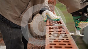 Worker builds a wall of colored brick. Worker in Close up of industrial bricklayer installing bricks and mortar cement brick on