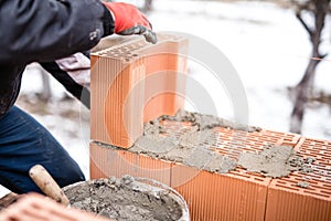 Worker buliding brick walls at house construction site, bricklayer photo