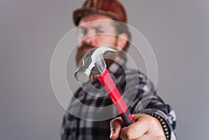 Worker, Carpenter or builder in hard hat with hammer. Selective focus. Bearded man in helmet hammering nail.