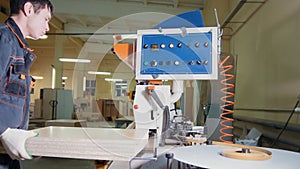 Worker carpenter handles wooden panels on the edging machine on the furniture factory