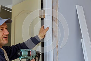 Worker carpenter at internal door installation with using nail gun