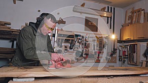 Worker carpenter man smoothing using electric wood planer machine in a joinery, manual labor.