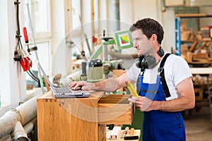 Worker in a carpenter's workshop with computer