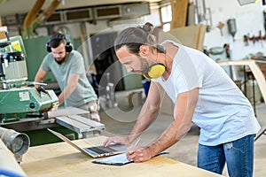 Worker in a carpenters workshop with computer