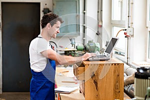 Worker in a carpenter's workshop with computer