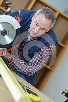 Worker in carpenters workshop using saw machine
