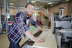 worker in carpenters workshop using saw machine