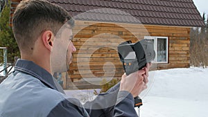 The worker carries out an inspection of the house the thermal imager. To look for losses of heat. Fight against