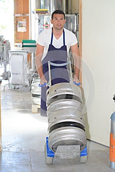 Worker carrying barrel with beer at brewery