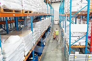 Worker carrying boxes on pallet jack in warehouse