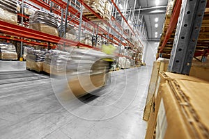 Worker carrying loader with goods at warehouse