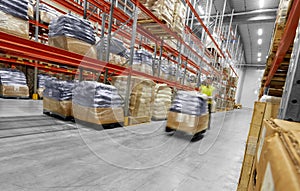 Worker carrying loader with goods at warehouse