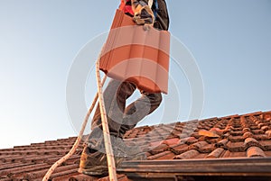 Worker carrying roof tile at the rooftop