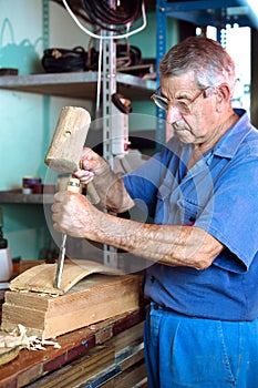 Worker carving wood with a chisel and hammer