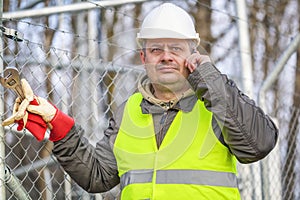 Worker with cell phone and adjustable wrench at outdoors