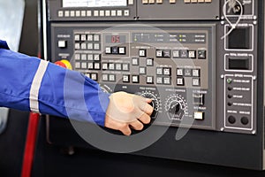 Worker changes feed override of CNC lathe machine photo