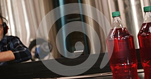 Worker checking juice bottles on production line