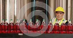 Worker checking juice bottles on production line
