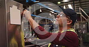 Worker checking machine next to production line