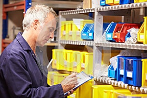 Worker Checking Stock Levels In Store Room