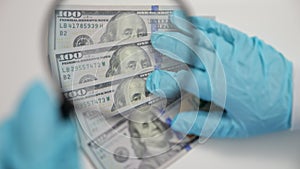 Worker checks money for fakeness with magnifying glass