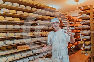A worker at a cheese factory sorting freshly processed cheese on drying shelves