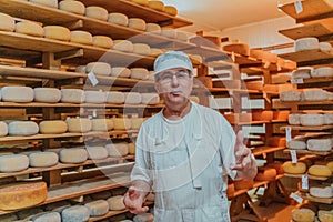 A worker at a cheese factory sorting freshly processed cheese on drying shelves