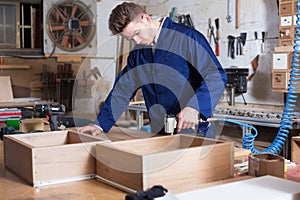 Worker chiseling plank at workshop