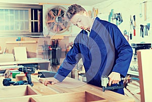 Worker chiseling plank at workshop