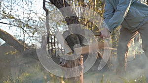 Worker chopping wood outdoors. An axe cuts through a wooden log in haze