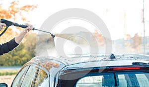 Worker cleaning car with high pressure water nozzle