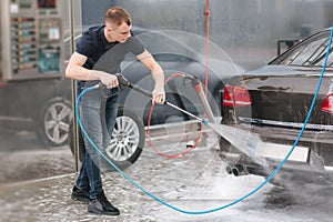 Worker cleaning car using high pressure water