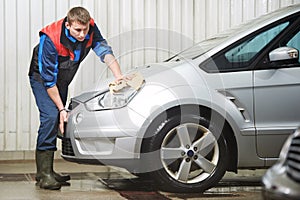 Worker cleaning car with water and sponge