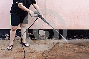 Worker cleaning dirty floor with high pressure washer