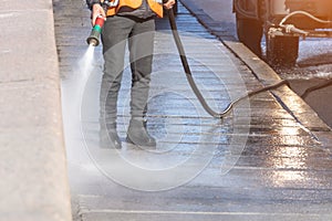 Worker cleaning driveway with gasoline high pressure washer splashing the dirt, granite embankment. High pressure cleaning