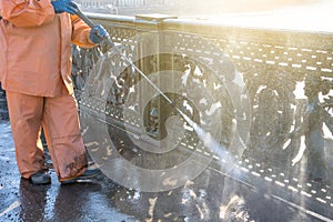 Worker cleaning driveway with gasoline high pressure washer splashing the dirt, railings, bumpers bridge. High pressure cleaning