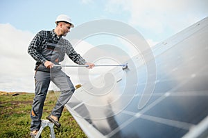 A worker cleaning dust and dirt form solar panels.