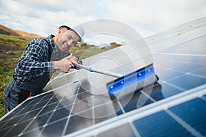 A worker cleaning dust and dirt form solar panels.