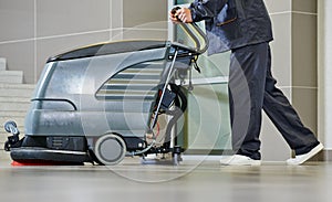 Worker cleaning floor with machine