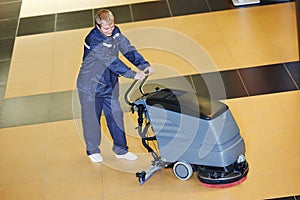 Worker cleaning floor with machine