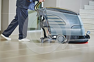 Worker cleaning floor with machine