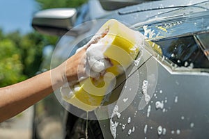 Worker cleaning a gray car outdoors